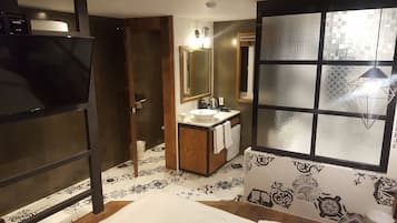 A bathroom with a large mirror, a sink, and a toilet. There is a window with a geometric pattern.