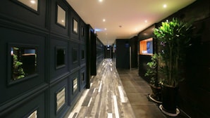 A hallway with dark walls, rectangular windows, and a tiled floor. - Hotel Yaja Jongno (Seoul)