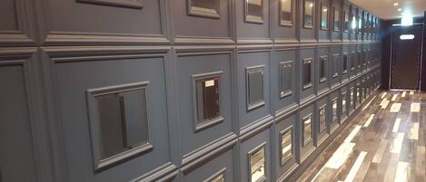 A hallway with a series of doors, each with a small window above the door.