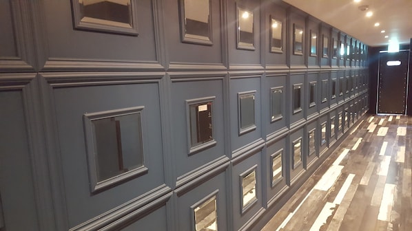 Un pasillo con varias puertas, cada una con un pequeño ventanal encima.