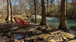 A riverside campsite with a clear view of a flowing river, surrounded by trees and rocks. - Bella Rosa Cottage - Stroll to Wimberley Square! Cypress Creek just steps away (Wimberley)