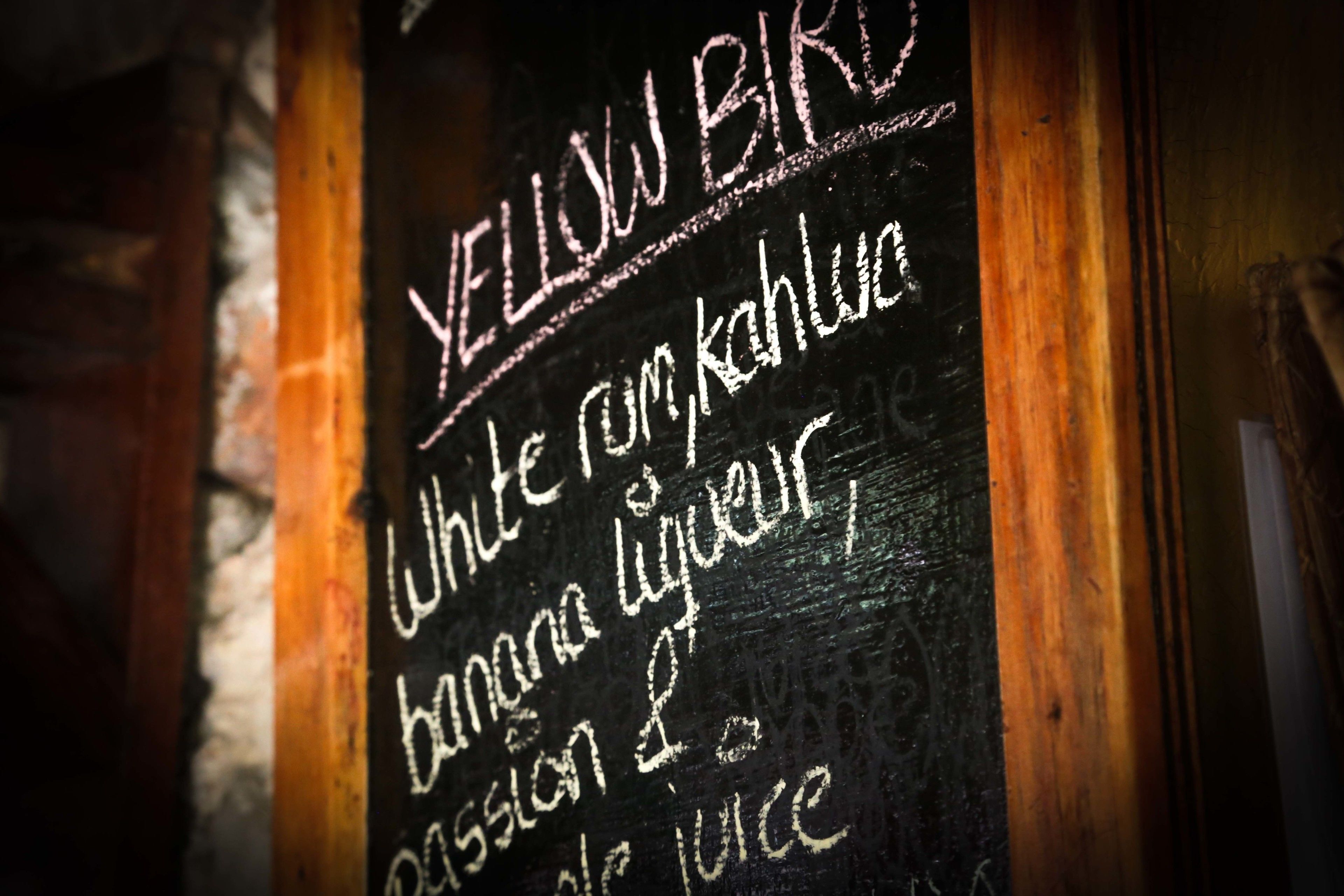 A chalkboard with a menu listing items such as 'White rum, kahu, banana liqueur, passion fruit juice'.
