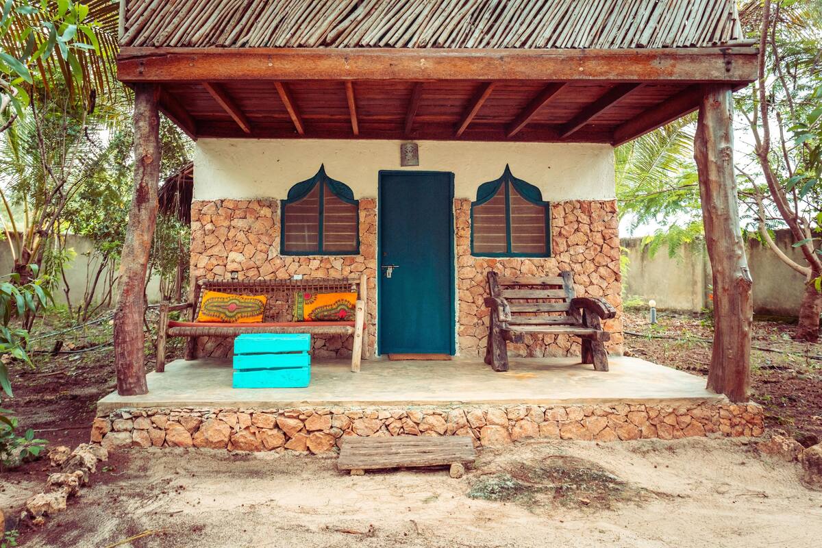 A rustic building with a stone facade, a wooden door, and two windows with decorative frames.