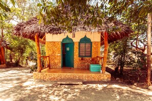 Un edificio rústico con techo de paja, fachada de piedra y puerta verde.