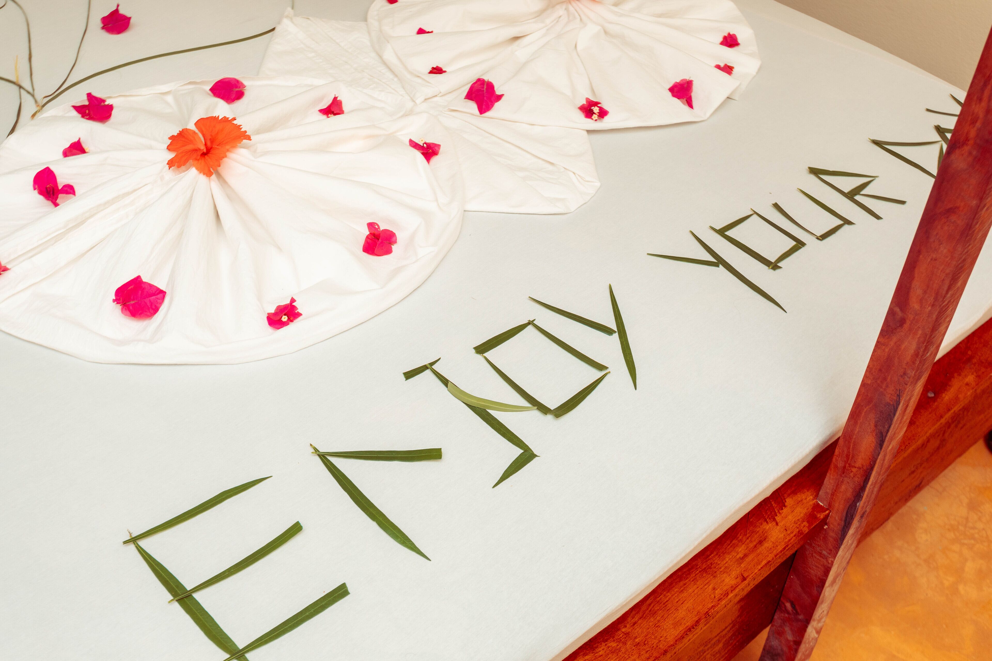 A table with a message "ENJOY YOUR DAY" and decorative elements like white cloths and pink flowers.