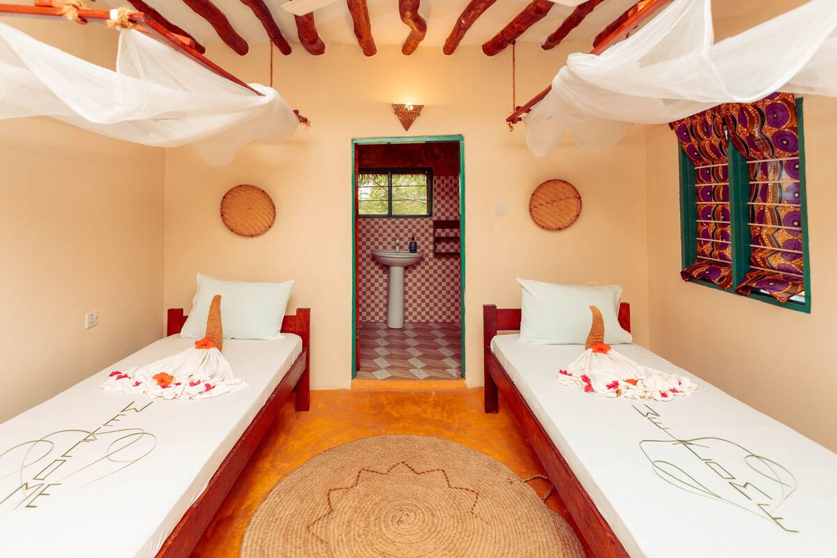 A room with two beds, a checkered floor, a sink, and a decorative wall.