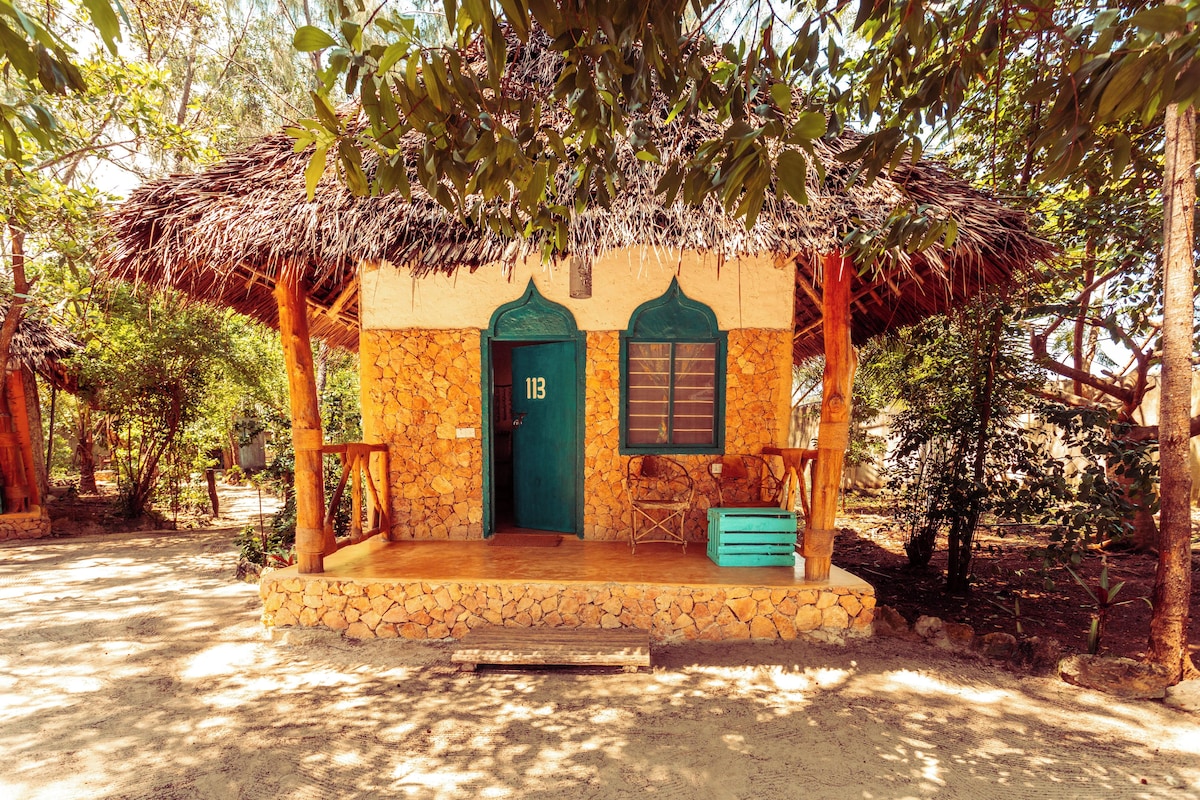 A rustic building with a thatched roof, a stone facade, and a green door.