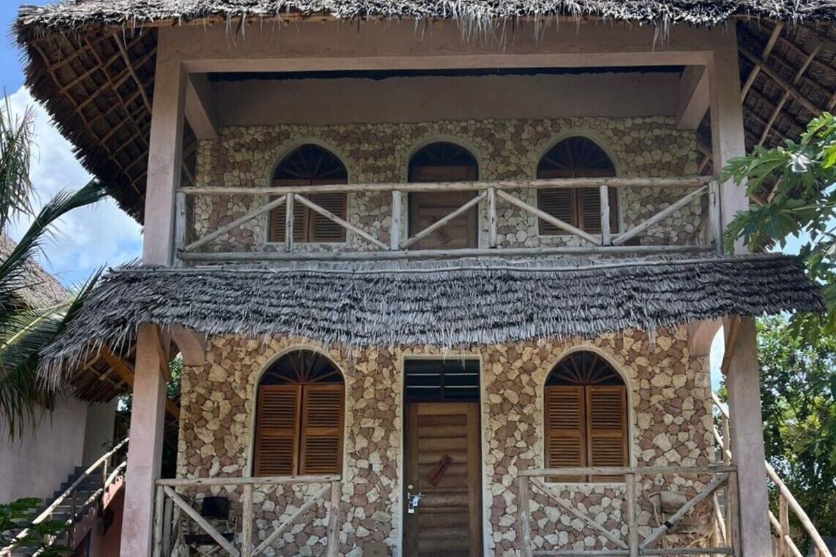 A two-story building with a thatched roof, stone walls, and wooden shutters.