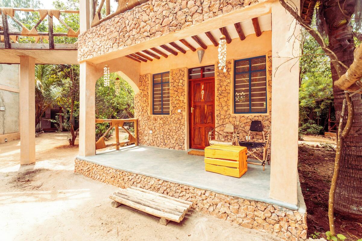 A stone building with a wooden door, a balcony, and a wooden bench.