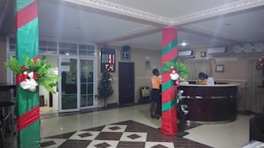 A reception area with a check-in counter, a Christmas tree, and decorative pillars. - Obaa'S Golden Plaza Hotel (New Abirem)
