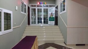 A hotel entrance with a staircase, a reception desk, and a sign advertising a Golden Hire Purchase service. - Obaa'S Golden Plaza Hotel (New Abirem)