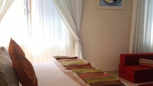 A bedroom with a bed, a red sofa, and a painting on the wall. - Obaa'S Golden Plaza Hotel (New Abirem)
