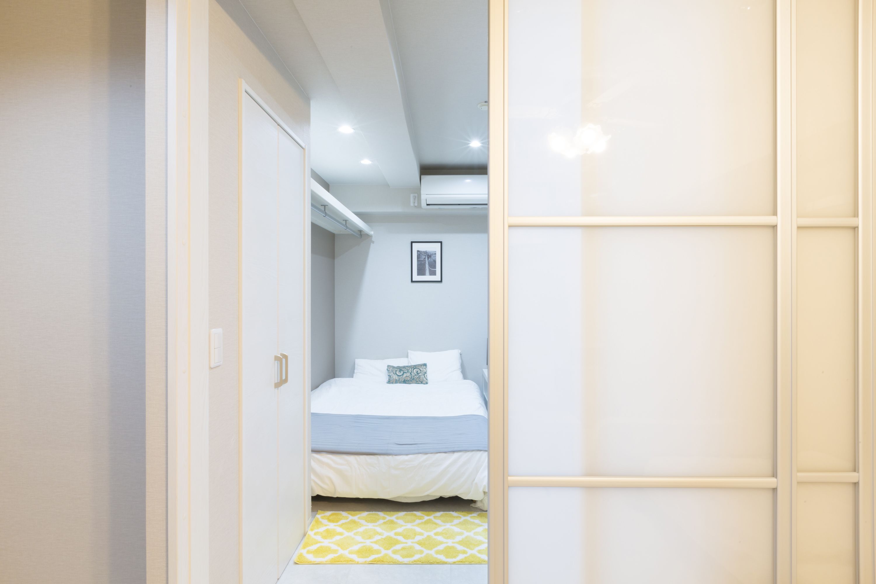 A bedroom with a bed, a bedside table, and a wall-mounted air conditioner.