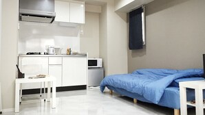 A compact room with a kitchenette, a bed, and a small table. - Jesus Square Nipponbashi (Osaka)