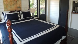 Une chambre avec un grand lit, une carte accrochée au mur, une porte coulissante et une petite table avec une lampe.