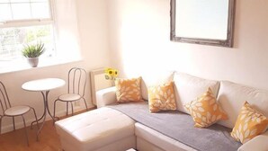 Un salon moderne avec un canapé d’angle, une table basse blanche et une petite table ronde avec des chaises.