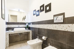 A modern bathroom with a white sink, a bidet, and a mirror. - Aeterna Suites Collection (Rome)