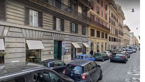 Vista de la calle con coches estacionados y edificios con toldos.