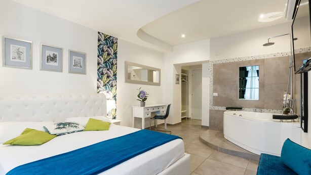 Una habitación de hotel moderna con una cama grande, un escritorio, un baño con bañera y ducha.