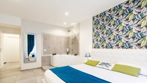 Una habitación de hotel con una cama grande, ducha, espejo y pared con diseño de hojas.