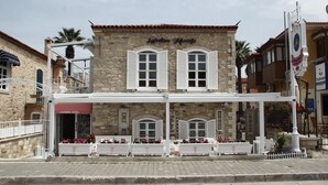 Edifici de pedra amb un rètol que diu "Laedran Hotel". Té una zona d'estar a l'aire lliure coberta amb bancs blancs i jardineres de flors.