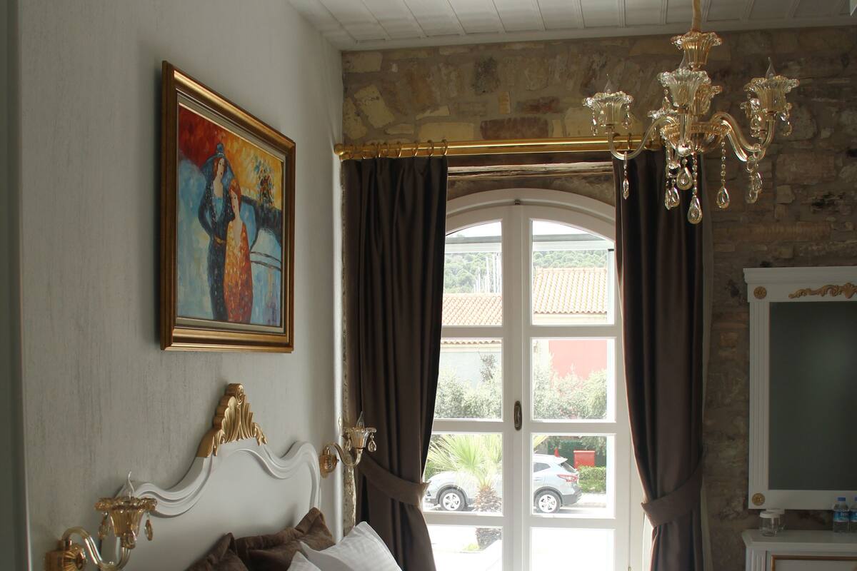 Une chambre à coucher avec un grand lit, un lustre, un tableau et un téléviseur.