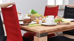 Una tavola imbandita per la colazione, con piatti, tazze e un cesto pieno di cibo.
