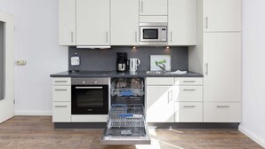 Una cucina moderna con mobili bianchi, forno integrato, microonde e lavastoviglie.
