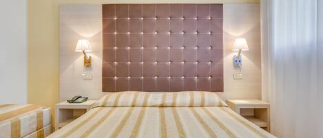 A hotel room with a large bed, two bedside tables, a telephone, and two wall-mounted lamps.