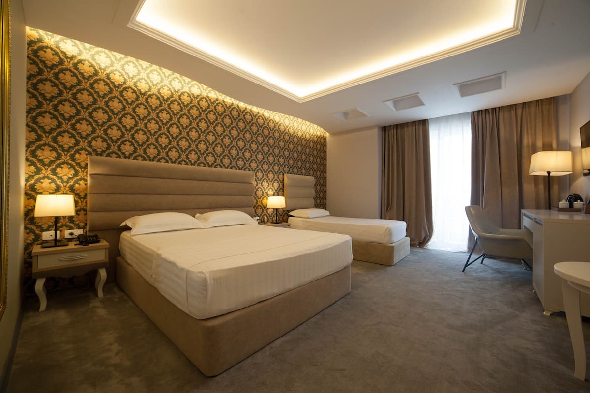 A hotel room with two beds, a desk, and a chair.