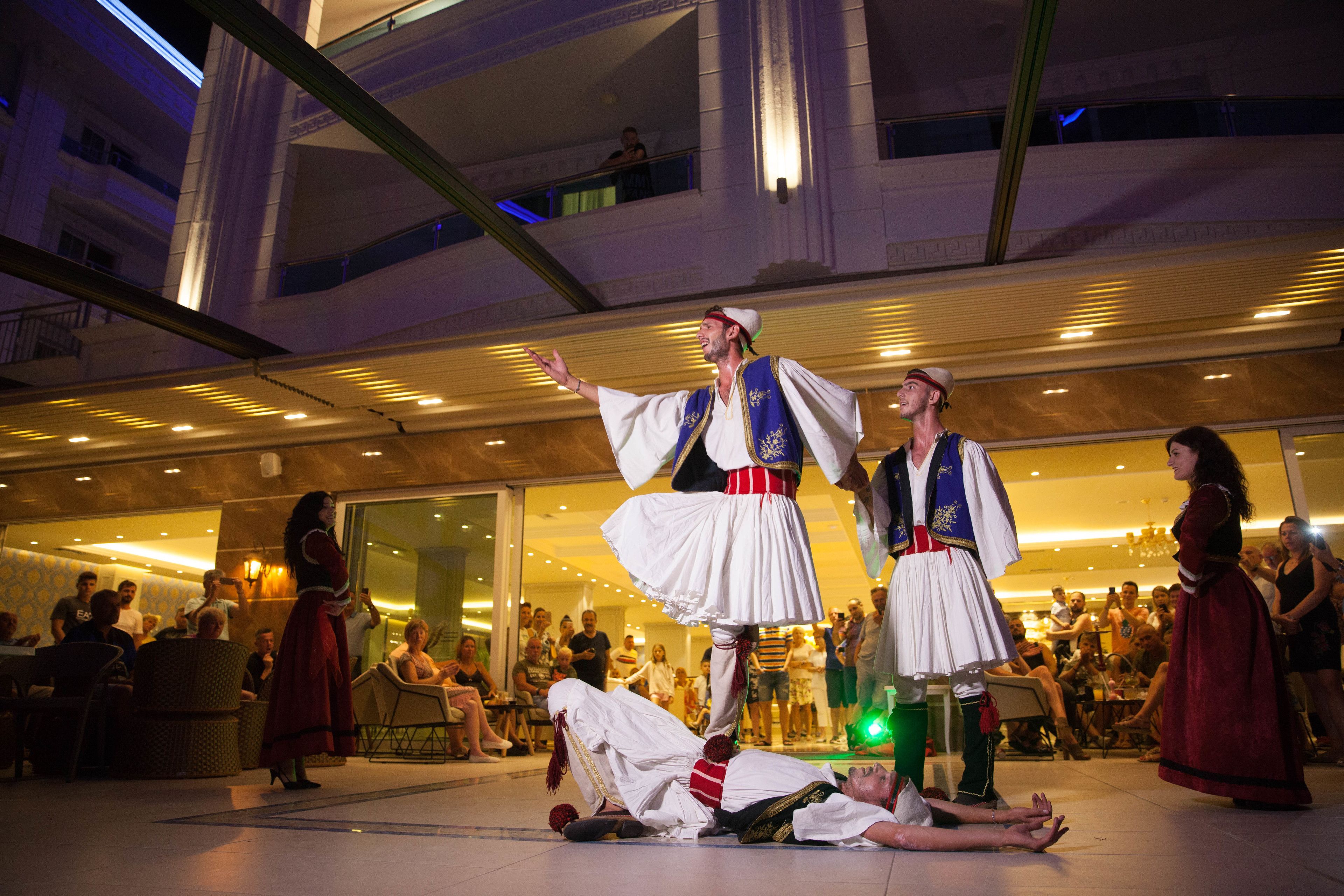 A performance with performers in traditional costumes in an indoor public space with a modern architectural design.