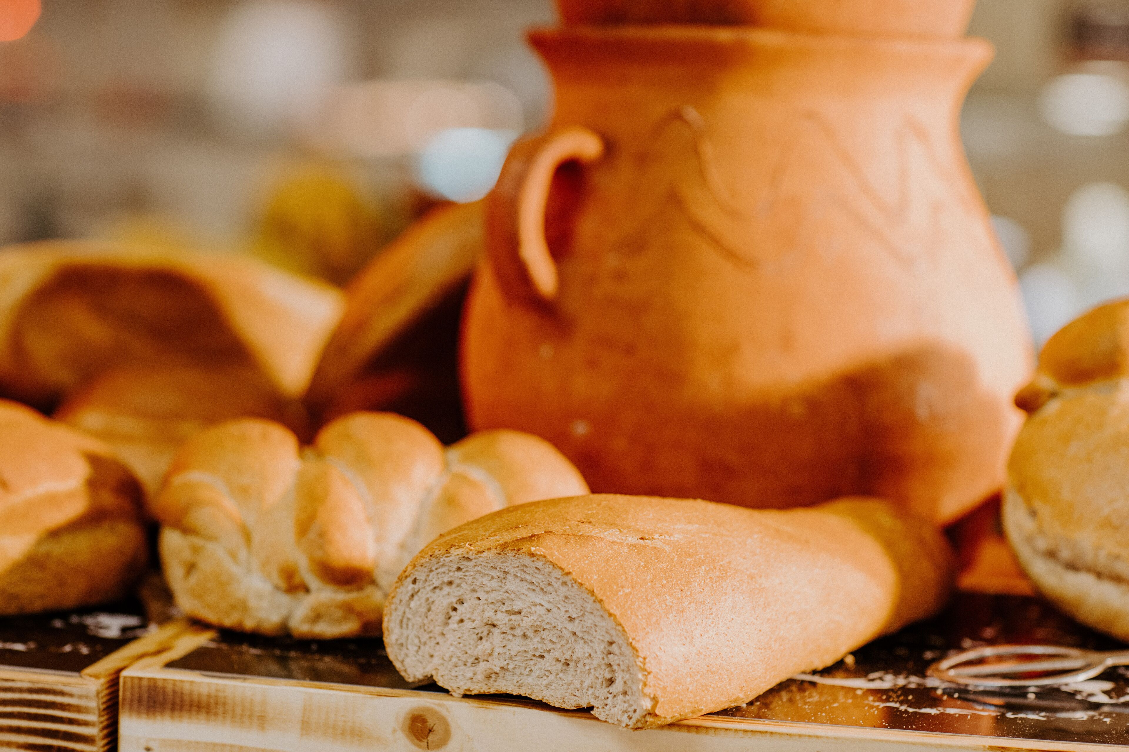 A loaf of bread and a clay pot on a wooden surface.