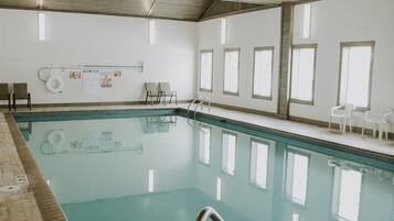 Een binnenzwembad met helder water, een post voor de badmeester en een betegeld zonnedek.