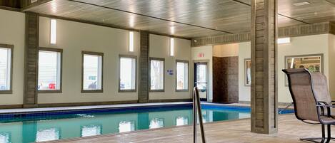 An indoor swimming pool with a tiled floor and a metal ladder.