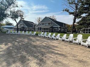 Une rangée de chaises Adirondack blanches est alignée devant un bâtiment dont le toit est gris et les bordures blanches.