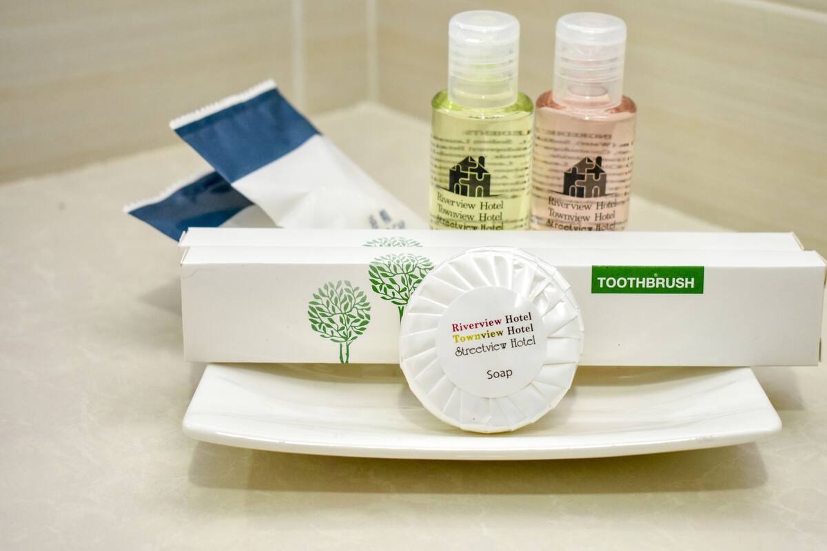 A toiletries set including a toothbrush, soap, and two bottles of liquid soap, all branded with the Riverview Hotel logo.