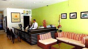 A hotel reception area with a reception desk, chairs, a sofa set, and framed pictures on the wall. - Streetview Hotel (Muar)