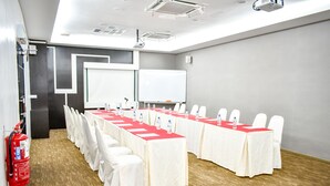 A conference room with a long table, white chairs, a whiteboard, and a projector. - Streetview Hotel (Muar)