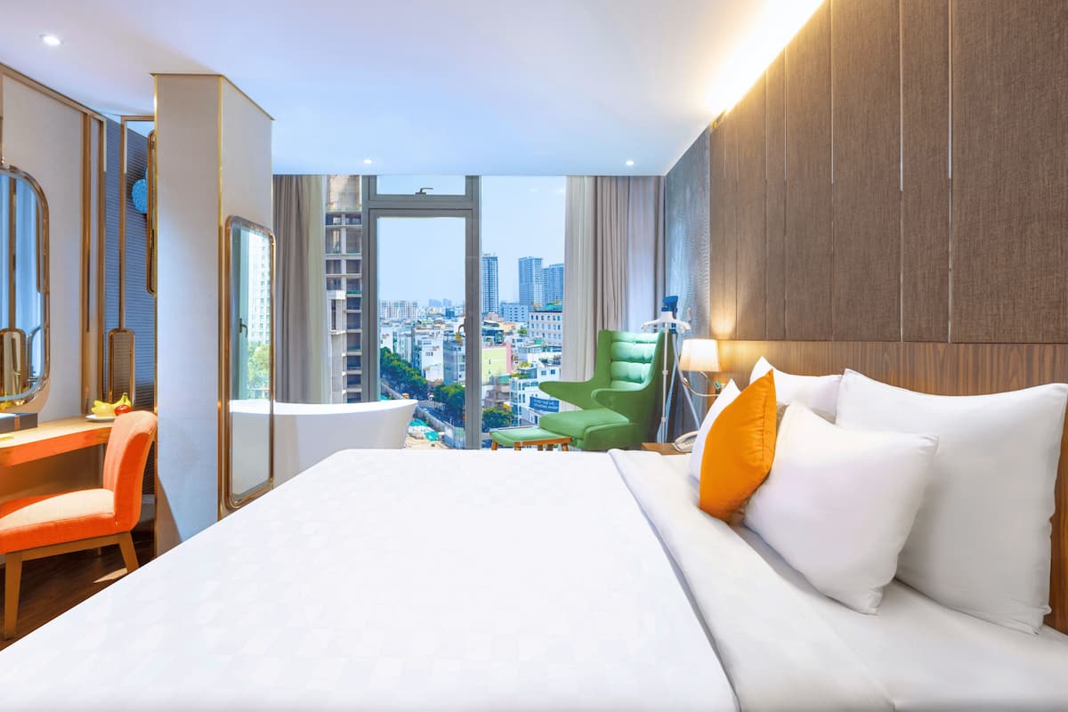 A hotel room with a large bed, a desk, a chair, and a view of the city.