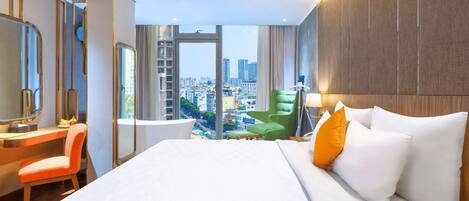 A hotel room with a large bed, a desk, a chair, and a view of the city.