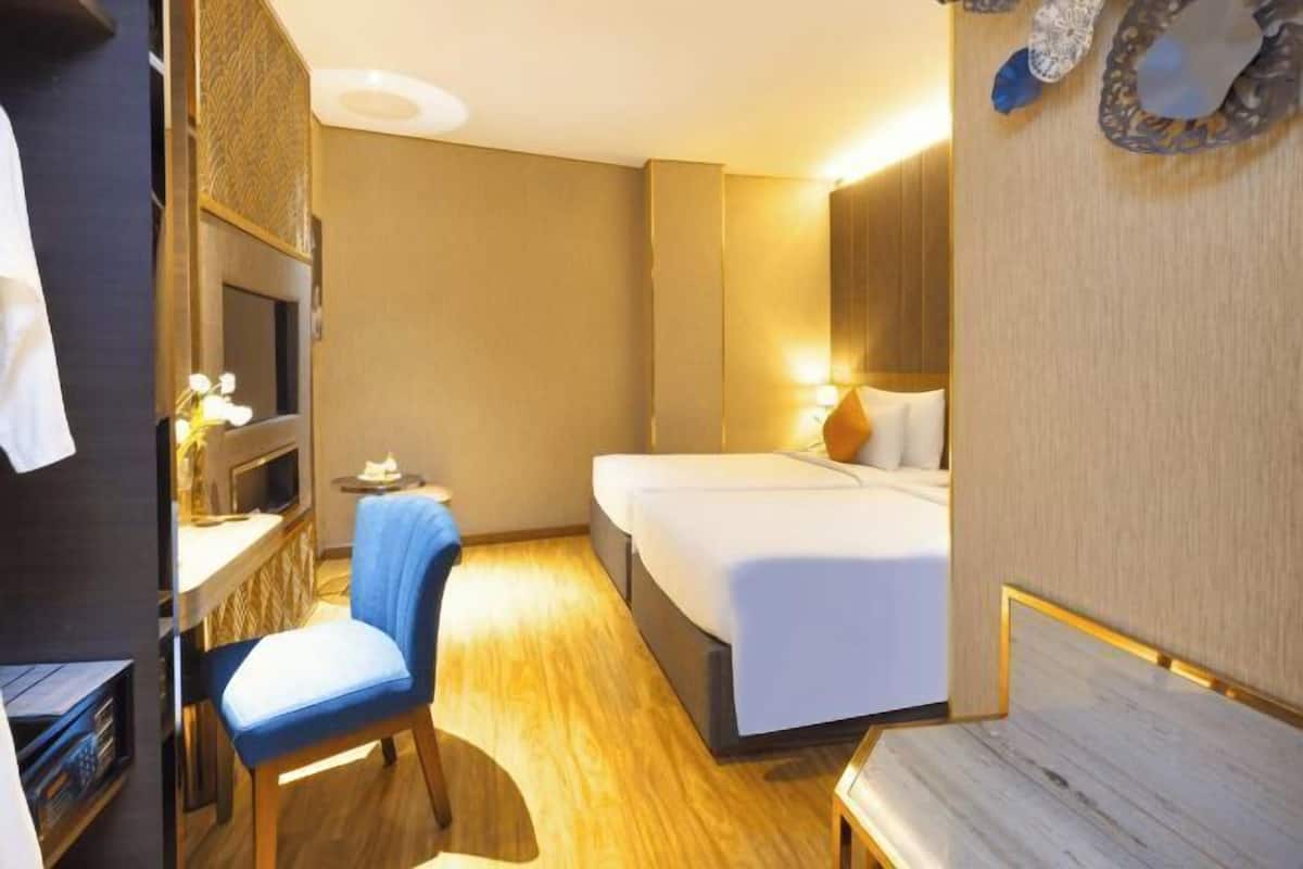 A hotel room with a bed, a desk with a chair, a television, and a mirror.