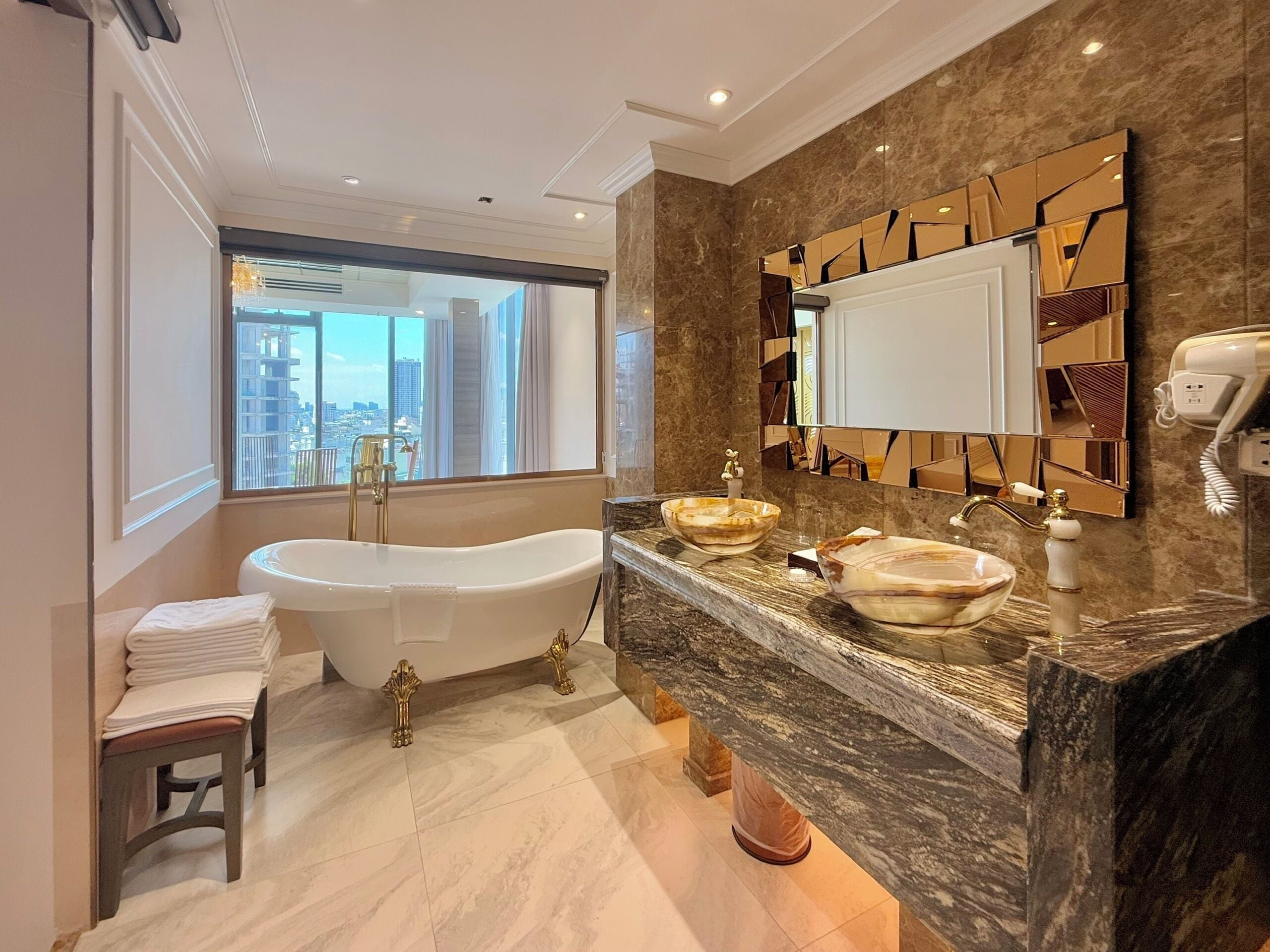 Un baño moderno con una bañera independiente, un espejo grande con diseños geométricos y una encimera de mármol.