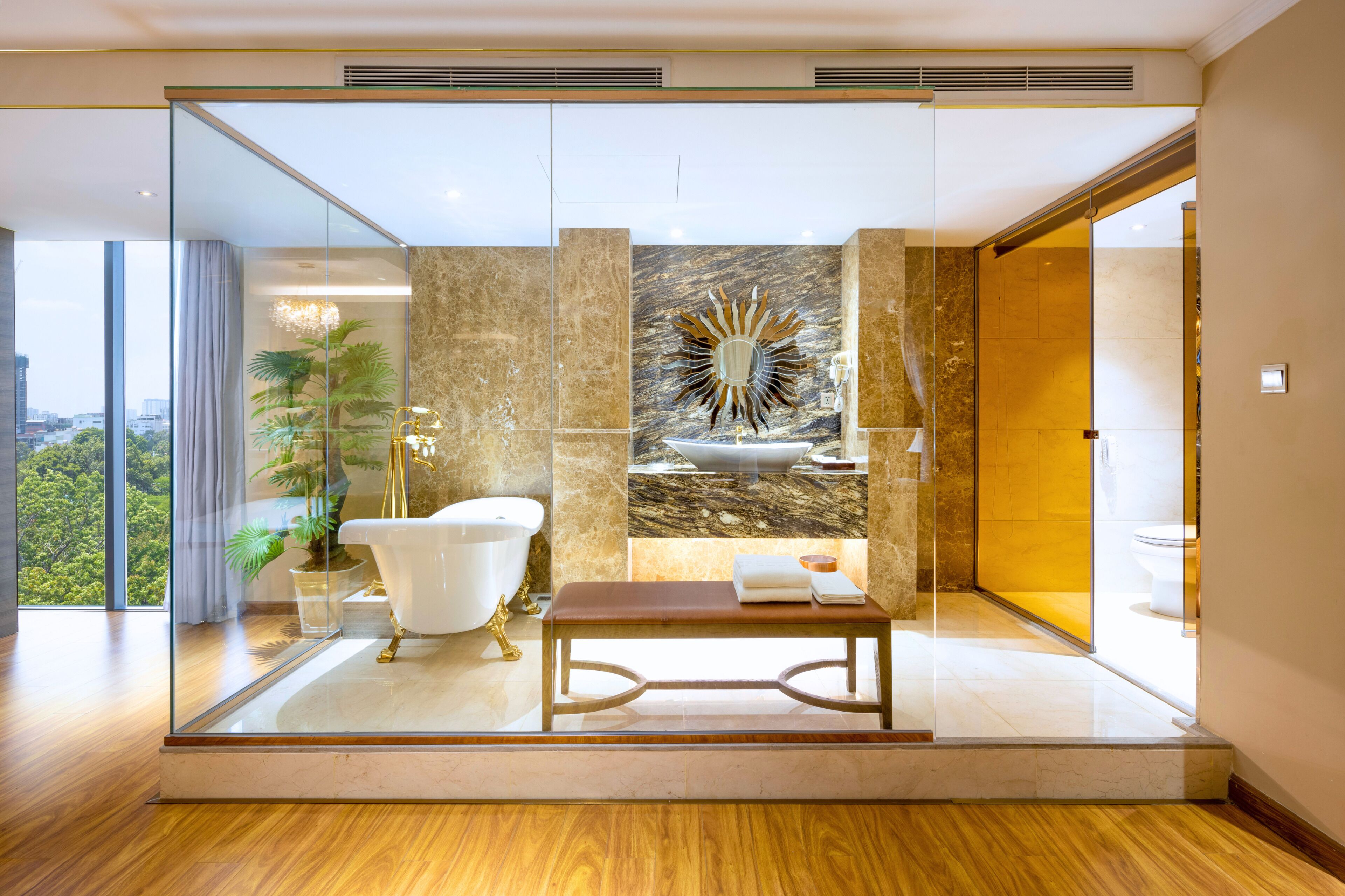 A modern bathroom with a freestanding bathtub, a marble wall, and a large window offering a city view.
