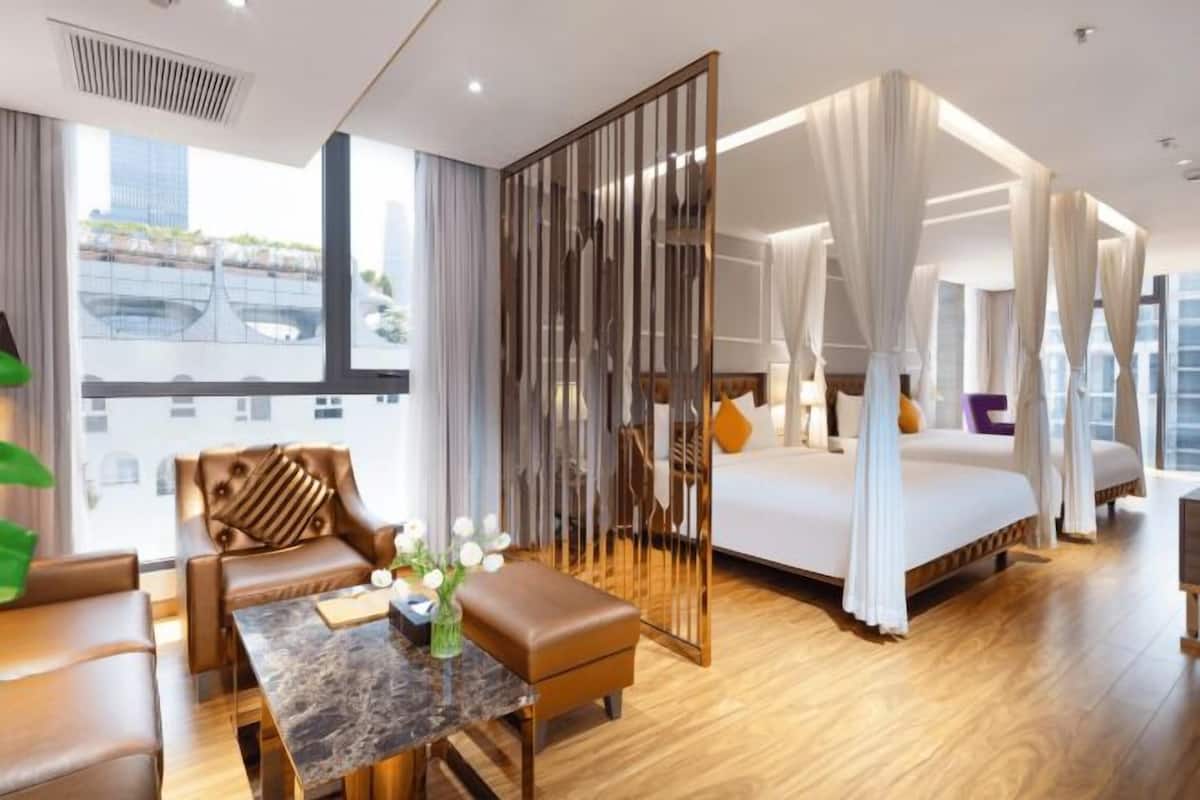 A modern hotel room with a large bed, a sitting area with a table, and a view of the city.