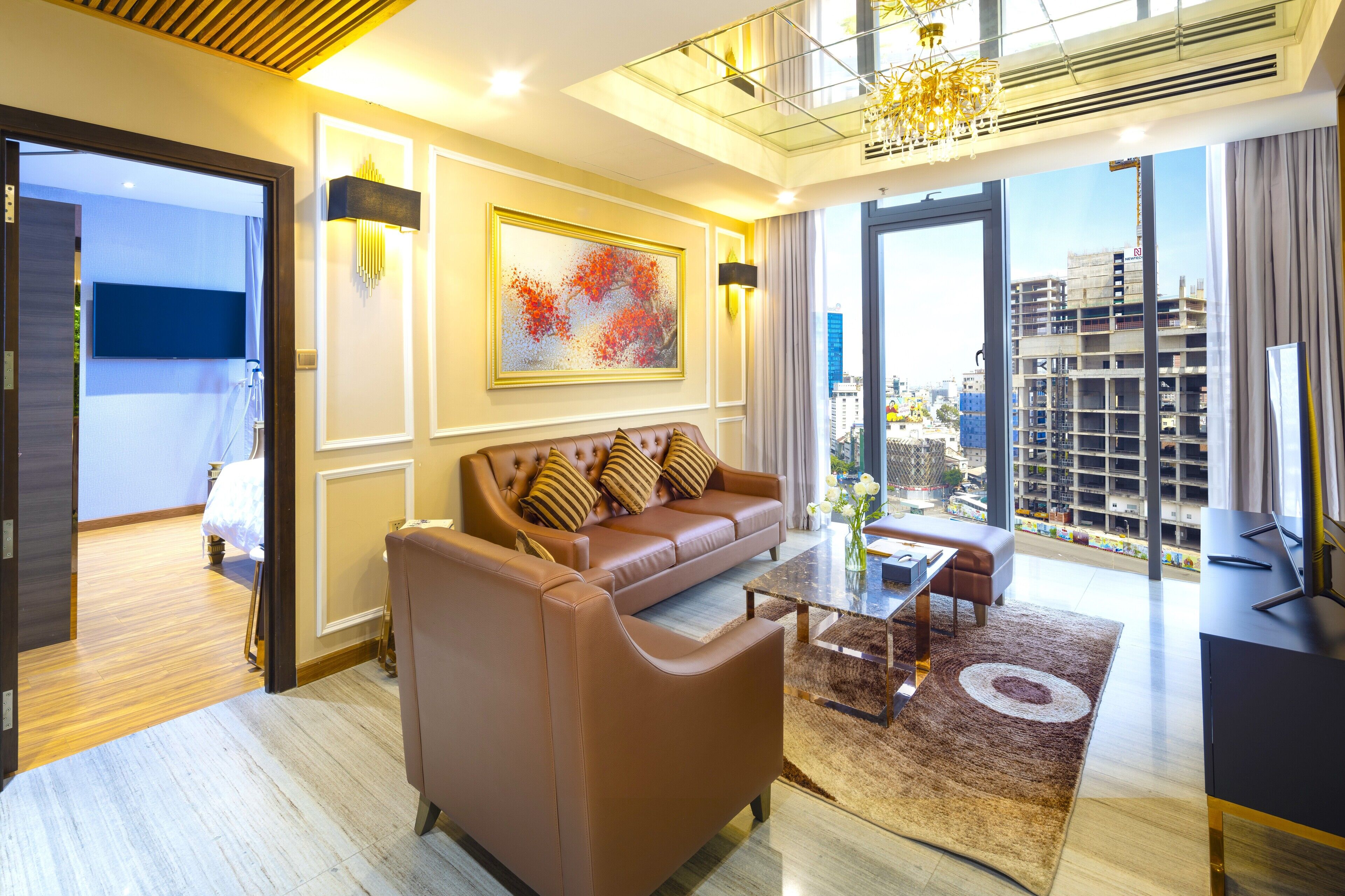 Una sala de estar moderna con un sofá de cuero marrón, una mesa de centro de vidrio y un ventanal con vista a la ciudad.
