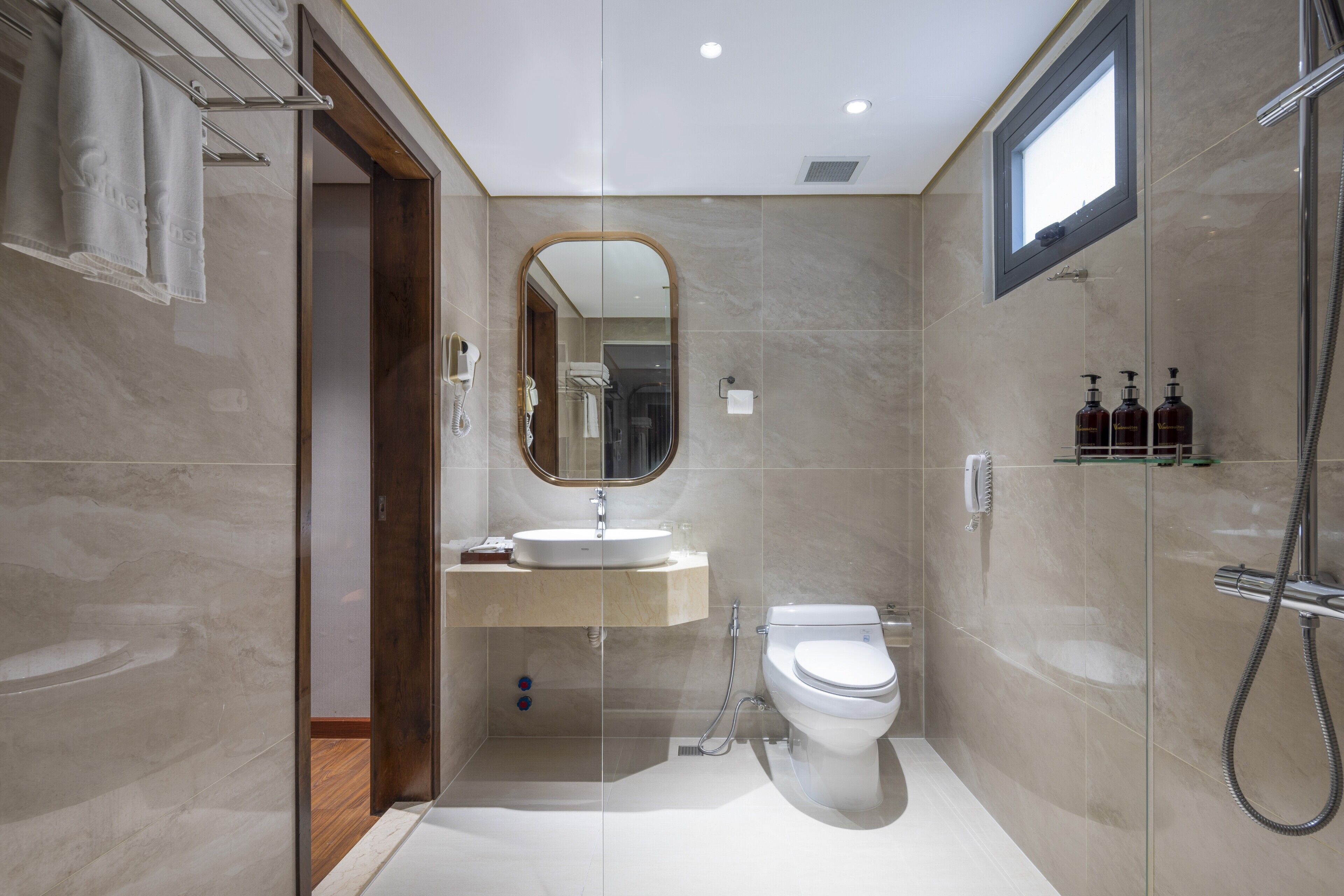 A modern bathroom with a glass-enclosed shower, a built-in sink, and a toilet.