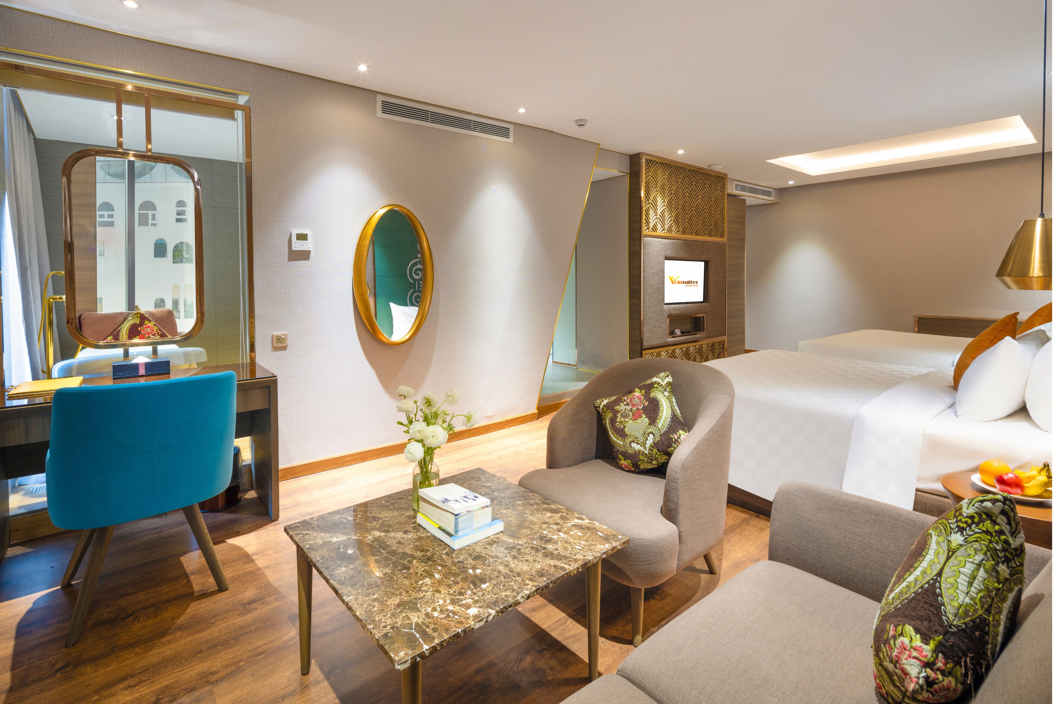 A hotel room with a bed, a desk, a chair, a sofa, a table, and a TV.