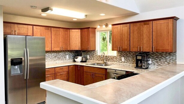 Una cocina moderna con armarios de madera, un refrigerador de acero inoxidable, lavavajillas integrado y una isla grande con pileta.