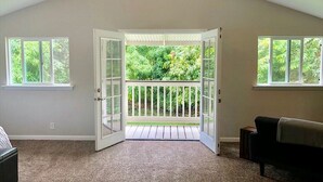 Puerta abierta que da a un balcón con vistas a vegetación.
