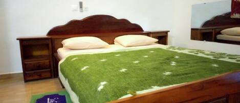 A bedroom with a wooden bed, a nightstand, a dresser, and a green rug.